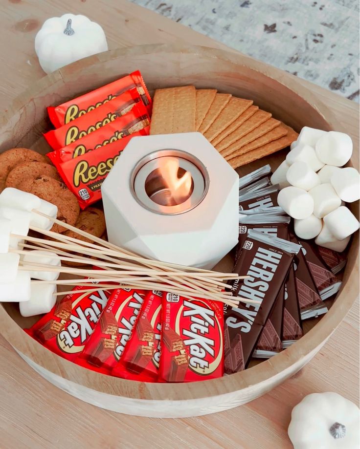 a wooden bowl filled with marshmallows, chocolate bars and other candy items