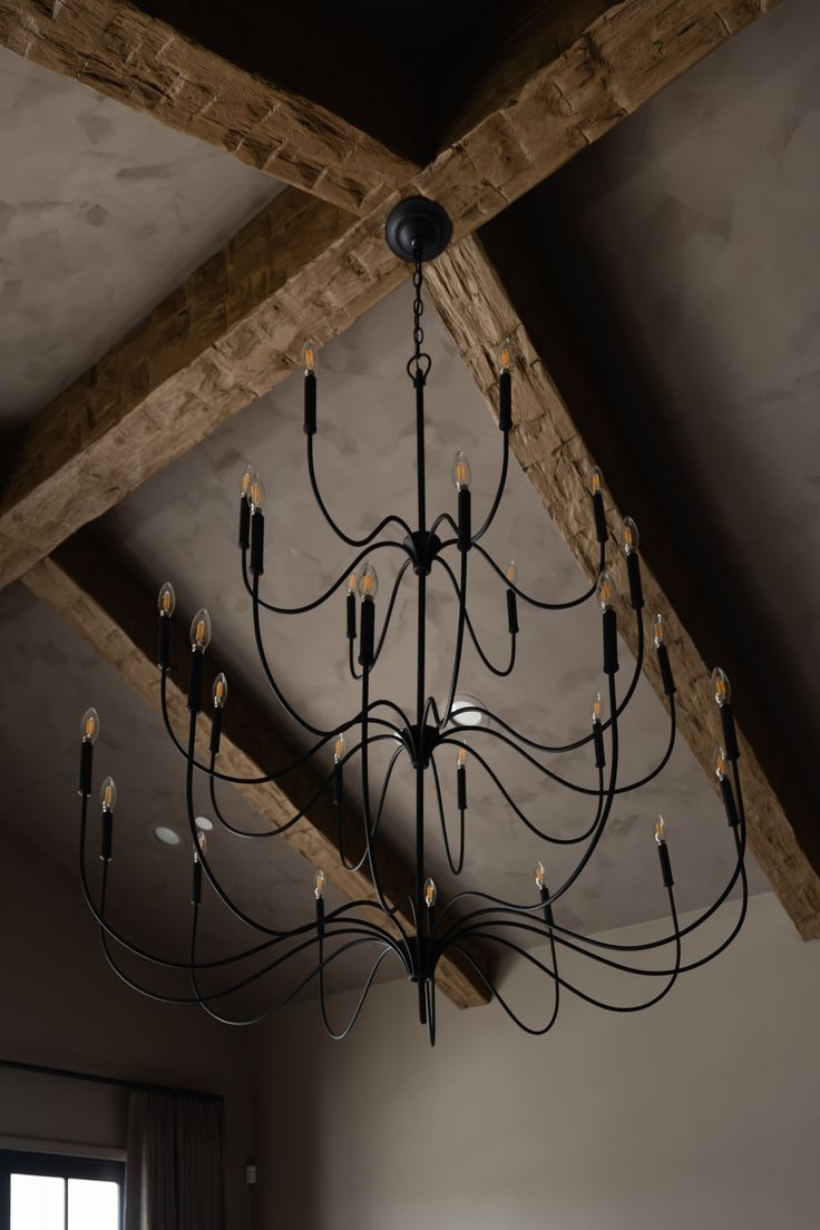 a chandelier hanging from the ceiling in a room with wood beams and windows