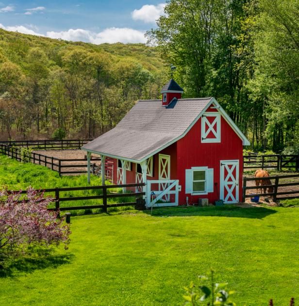 a red barn sits in the middle of a lush green field