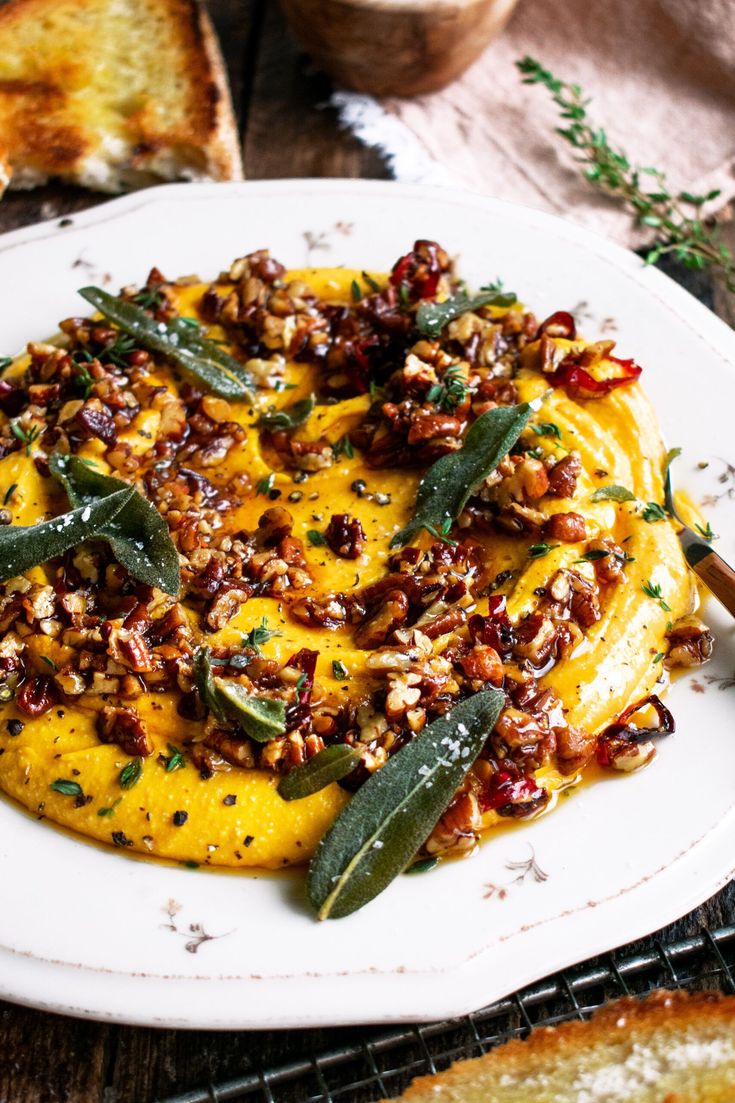 a white plate topped with food and garnished with nuts, herbs and seasonings