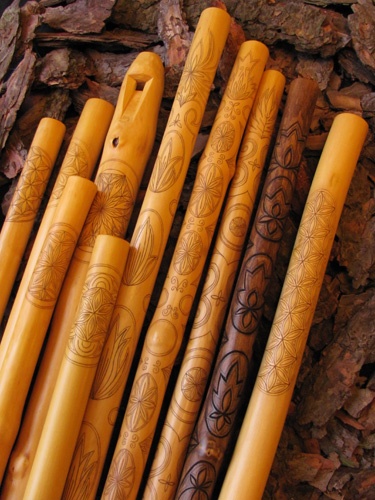 several wooden sticks with designs on them sitting next to some rocks and tree barks