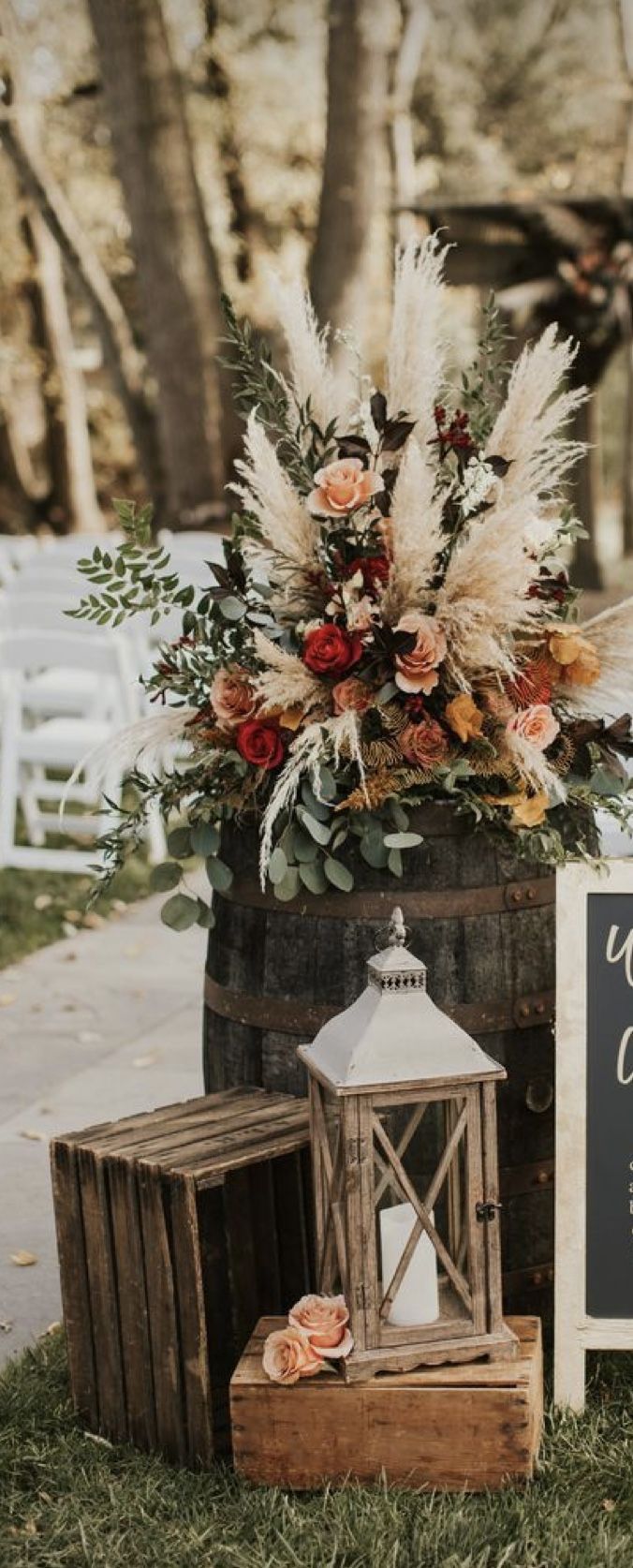 an outdoor ceremony setup with flowers, candles and chalkboard sign on the grass next to it