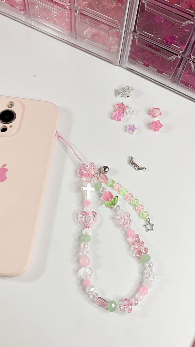 a pink phone case sitting on top of a table next to some beads and charms