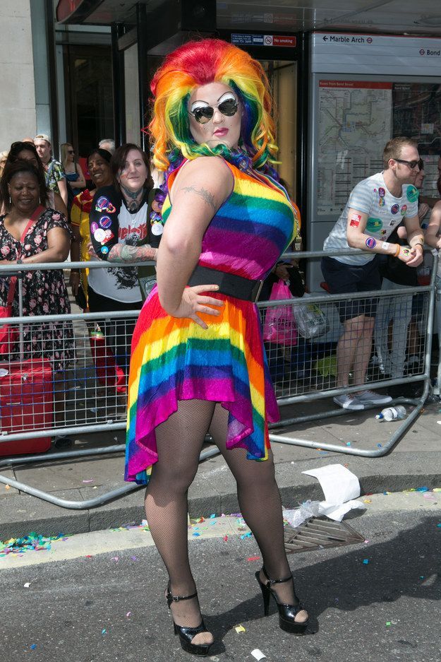 a woman in a rainbow colored dress standing on the street