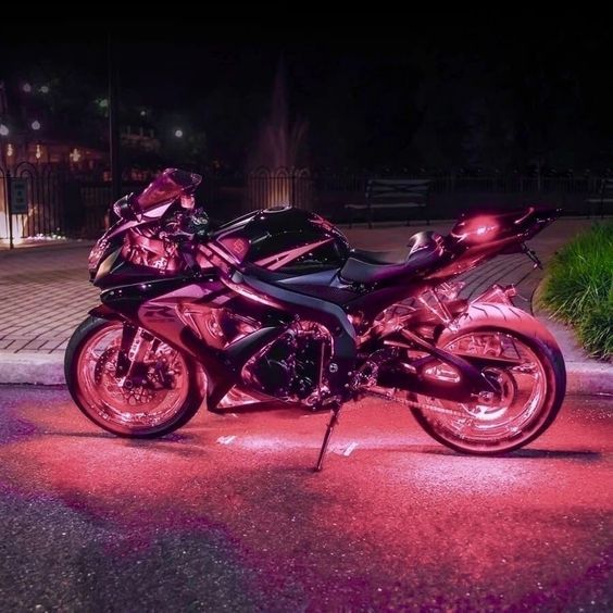 two motorcycles parked next to each other in the street at night time with lights shining on them