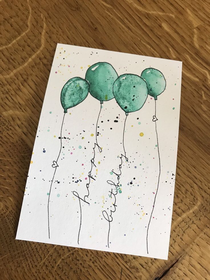 some green balloons are floating in the air on top of a wooden table with watercolor paint