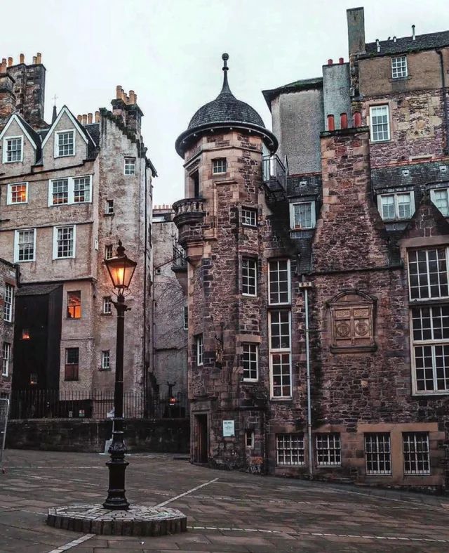 an old stone building with many windows and a lamp post in the middle of it