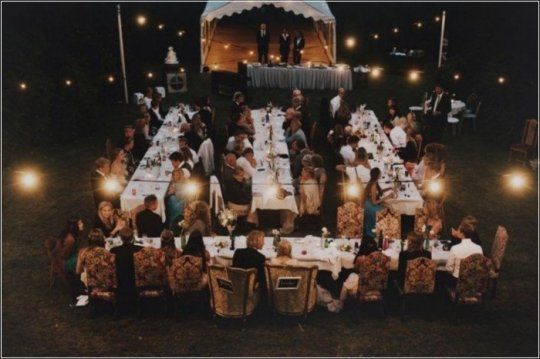 a large group of people sitting at tables in the middle of an outdoor tented area