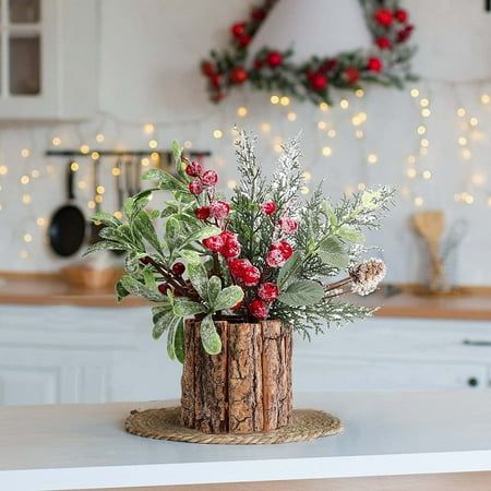 a wooden vase with red berries and greenery sits on a table in front of a kitchen decorated for christmas