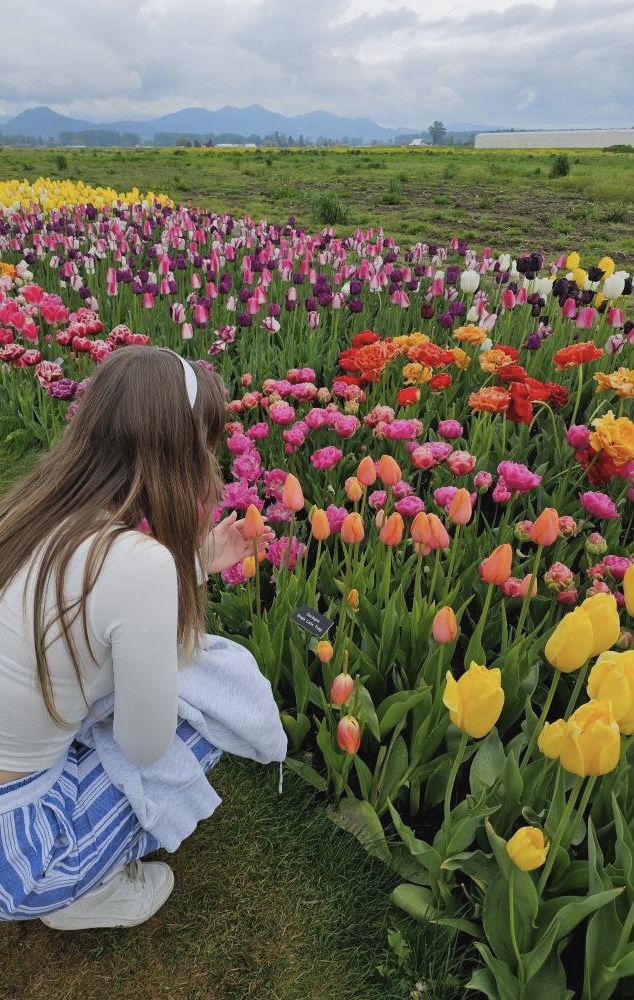 a woman kneeling down in front of a field of flowers