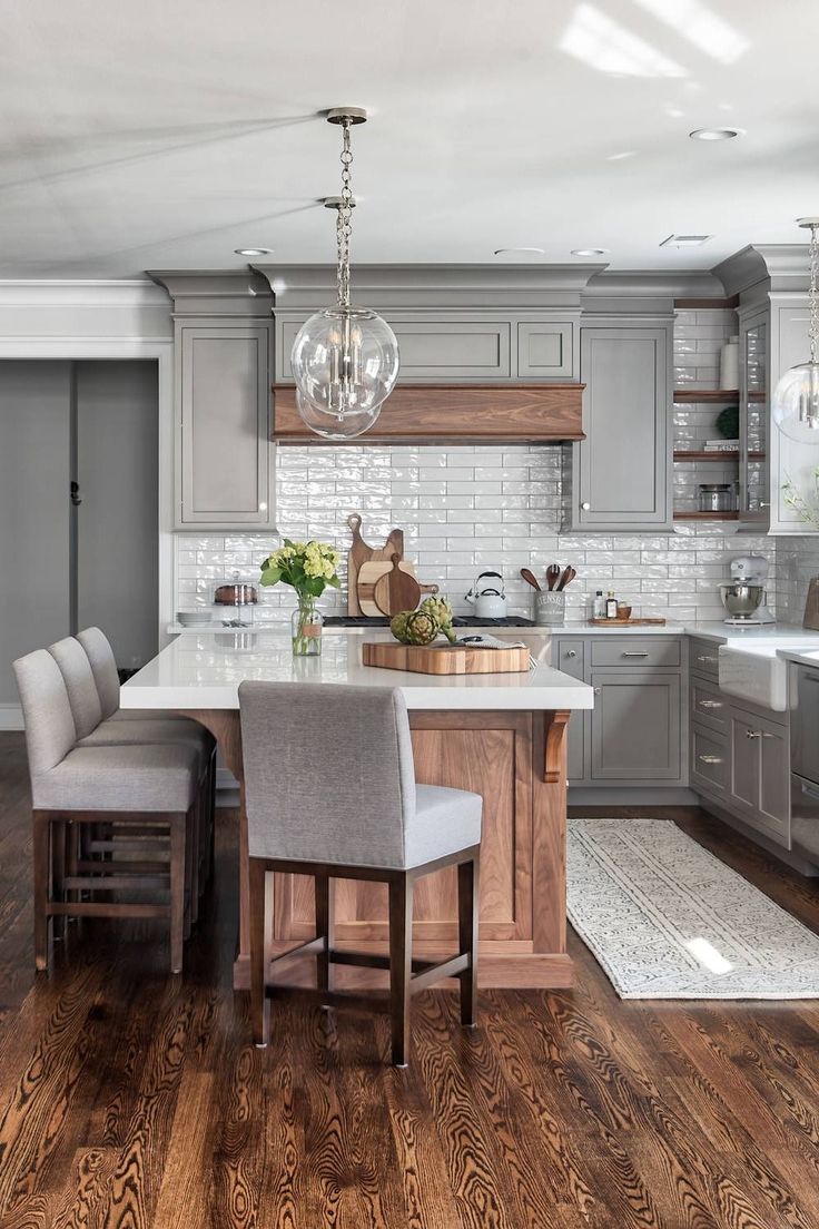 a large kitchen with gray cabinets and white counter tops, wooden flooring and an island in the middle