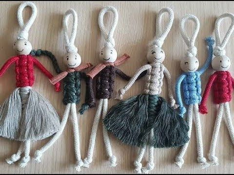 six small knitted dolls are lined up on a table top, each with different colored yarns