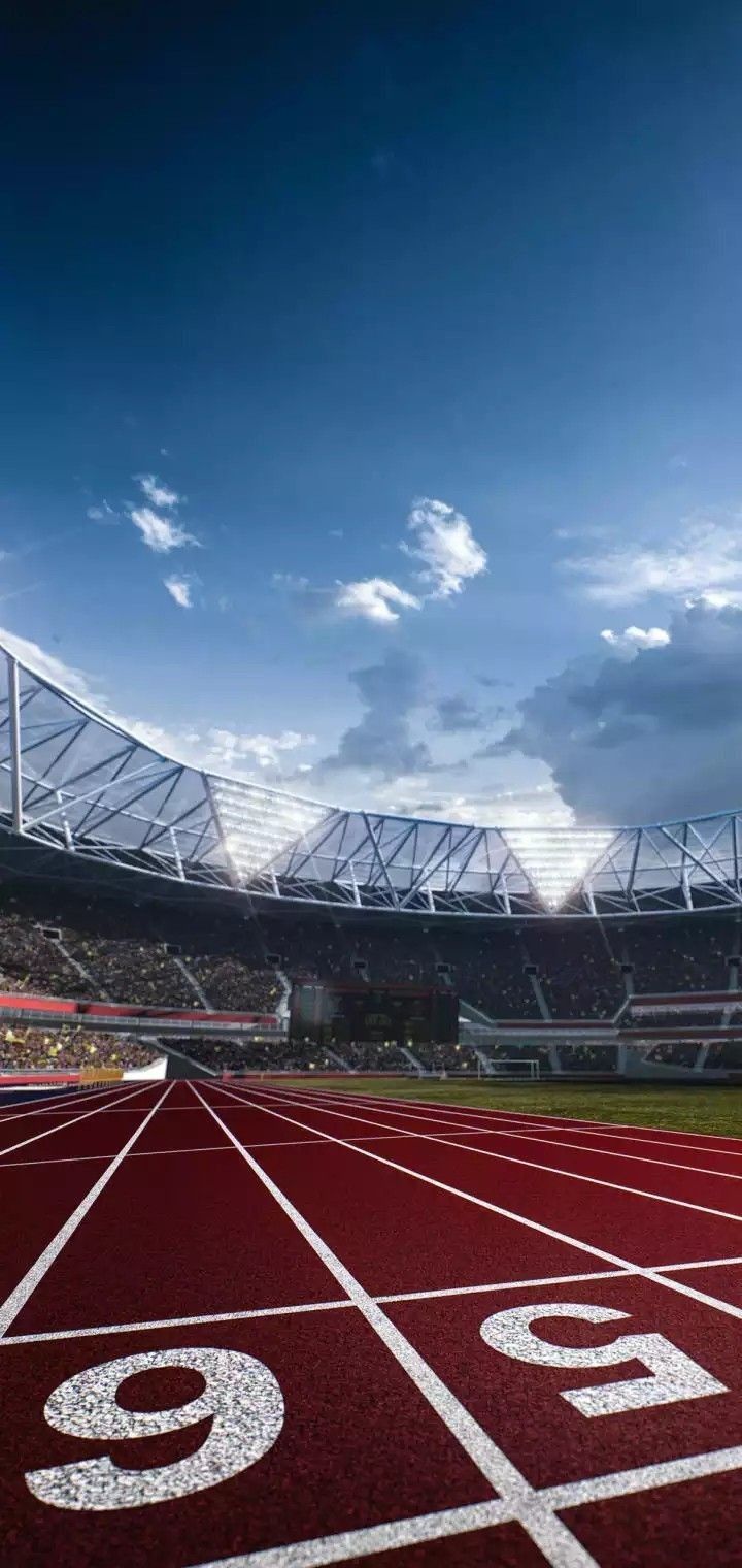 an empty stadium filled with lots of red and white running tracks under a cloudy blue sky