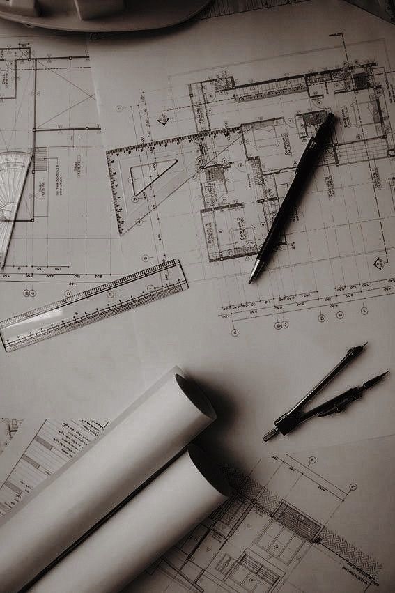 some tools are laying on top of blueprints and paper with architectural drawings in the background