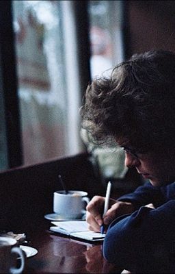 a man sitting at a table writing on a notepad