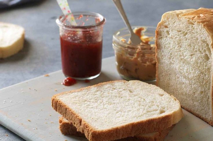 a loaf of bread sitting on top of a cutting board next to a jar of peanut butter