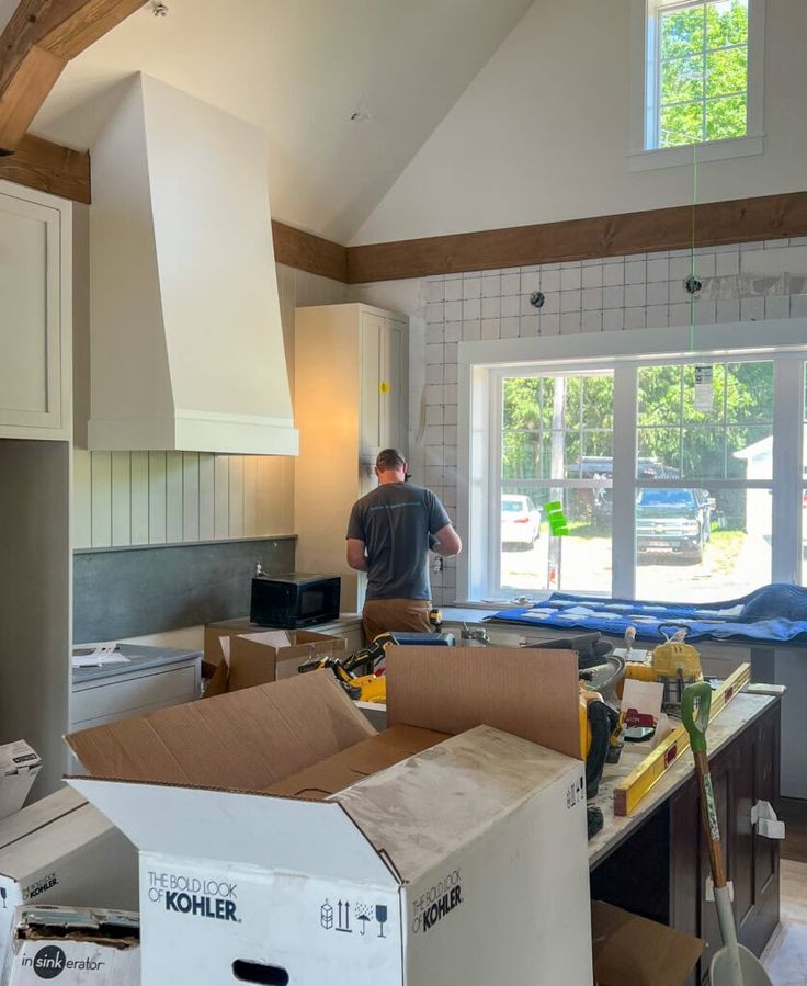 a man standing in a kitchen with boxes on the counter