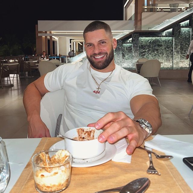 a man sitting at a table with a bowl of food in front of his face