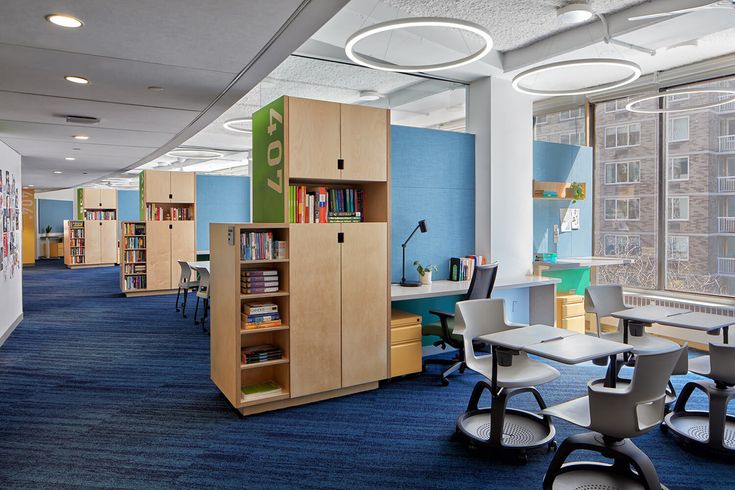 an office with desks, chairs and bookshelves in the middle of it