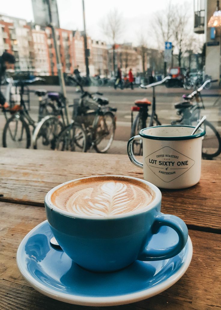 a cup of coffee sitting on top of a blue saucer next to a wooden table