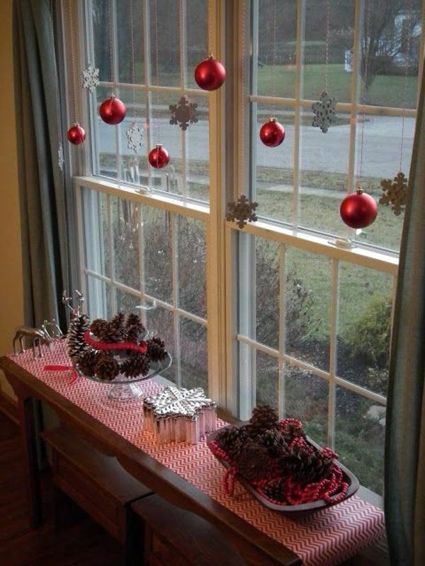 two red christmas decorations sitting on top of a window sill next to a table