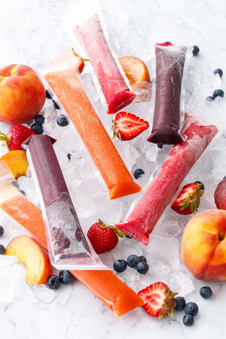 fruit and ice are on the table with some strawberries, peaches, and blueberries