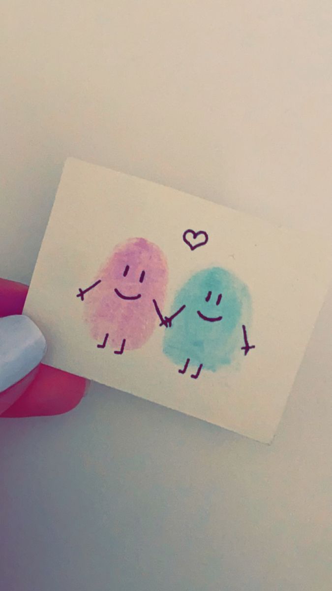 a hand holding a piece of paper with two cartoon characters drawn on it and the other one has a smiley face