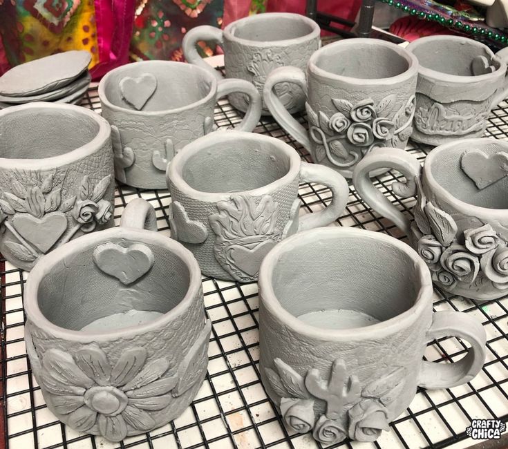 a table topped with lots of grey cups and saucers on top of a counter