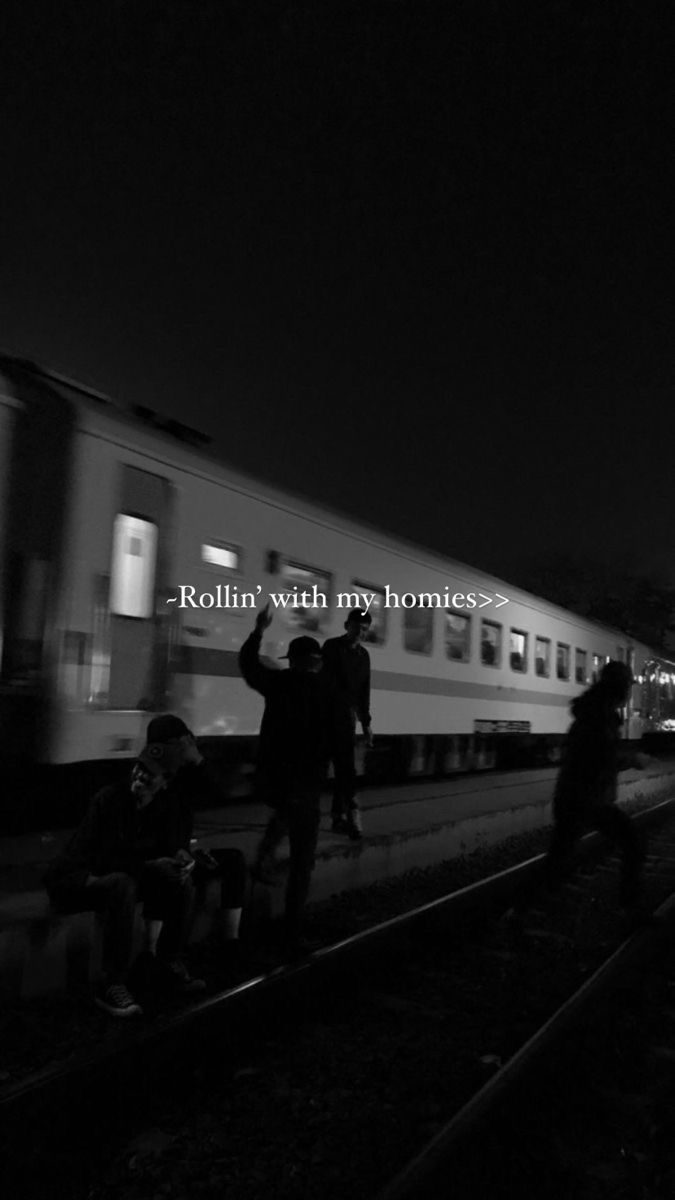 black and white photograph of people sitting on the train tracks at night with text reading rollin'watch my homes