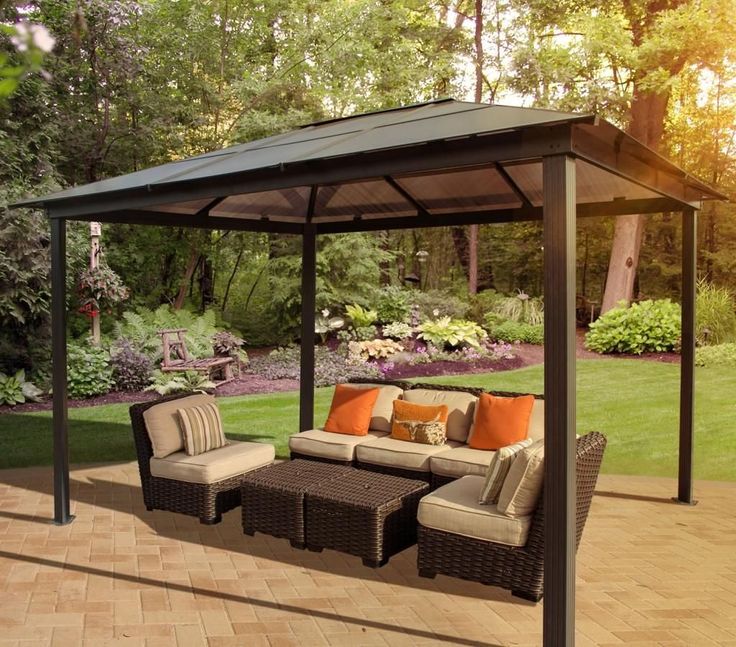 a couch and table on a patio under a gazebo in the middle of a yard