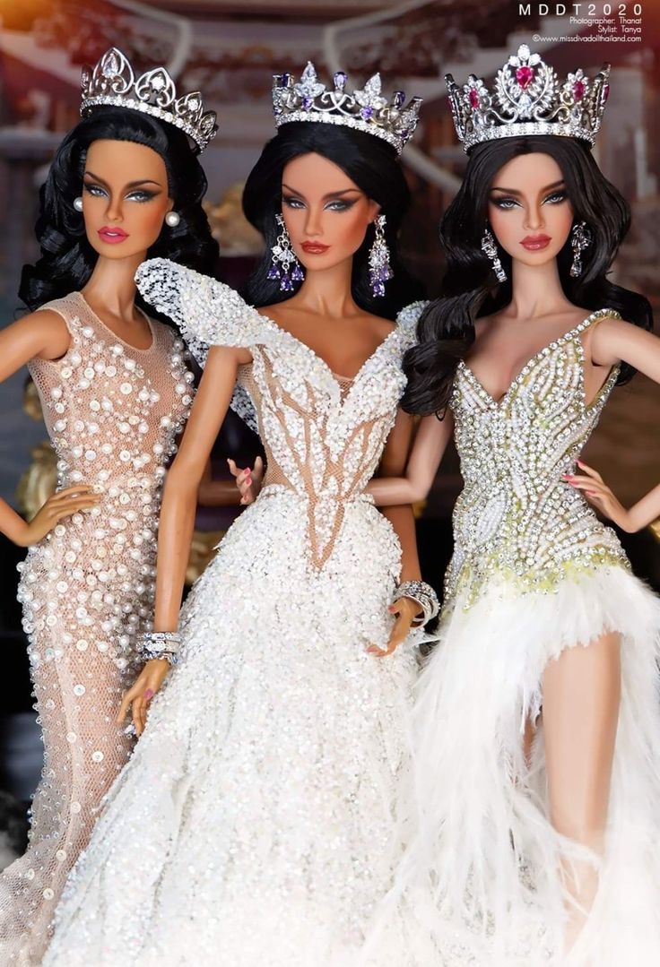 three barbie dolls dressed in white dresses and tiaras, standing next to each other