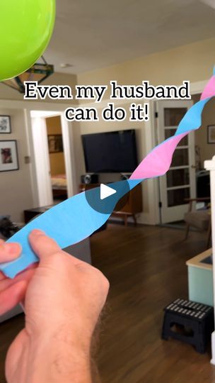 a person holding a blue and pink toothbrush in front of a living room filled with furniture