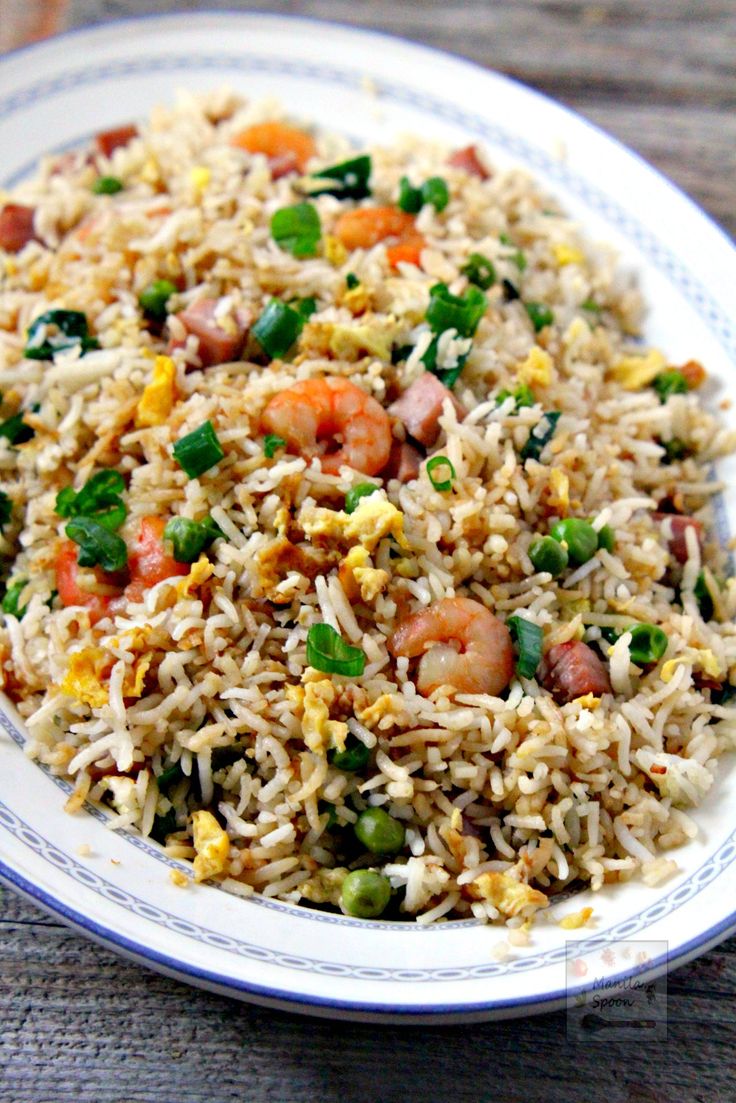 a white plate topped with fried rice and veggies on top of a wooden table