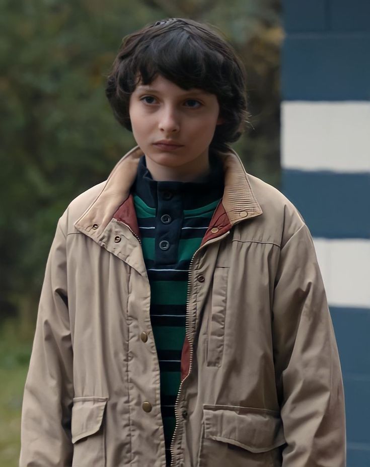 a young boy wearing a jacket and striped shirt