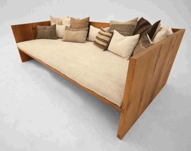 a wooden couch with many pillows on it