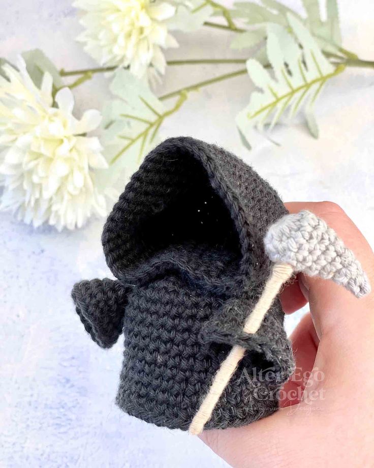 a hand holding a tiny crocheted doll with an angel wing on it's head