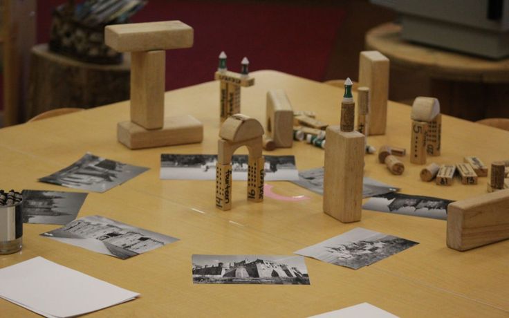 a wooden table topped with lots of pictures and pencils on top of it's sides