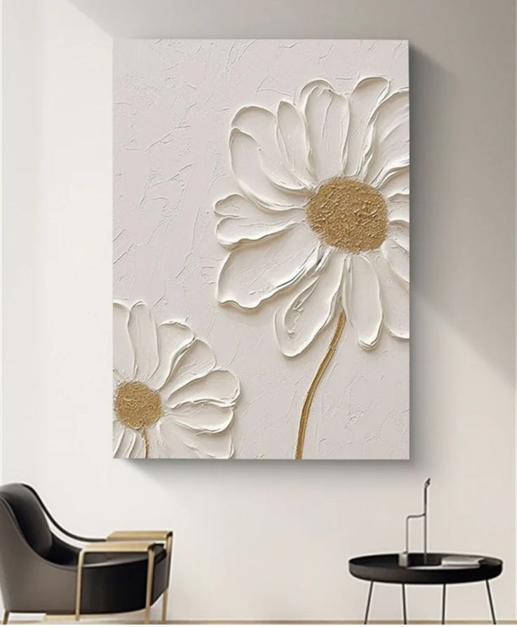 a white and gold flower painting on a wall above a chair in a living room