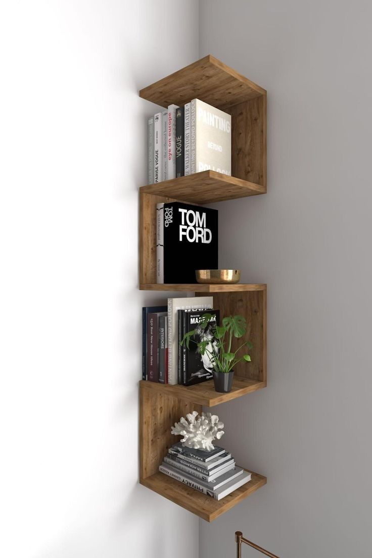 three wooden shelves with books and magazines on them in a corner next to a white wall