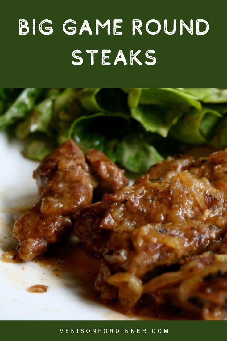 a white plate topped with meat covered in gravy next to a green salad