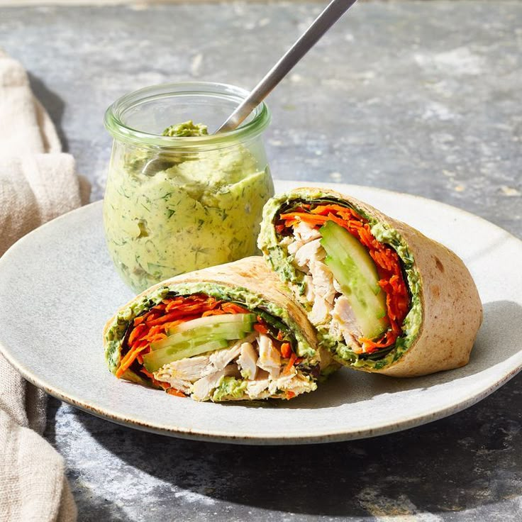 a sandwich cut in half on a plate with a jar of guacamole