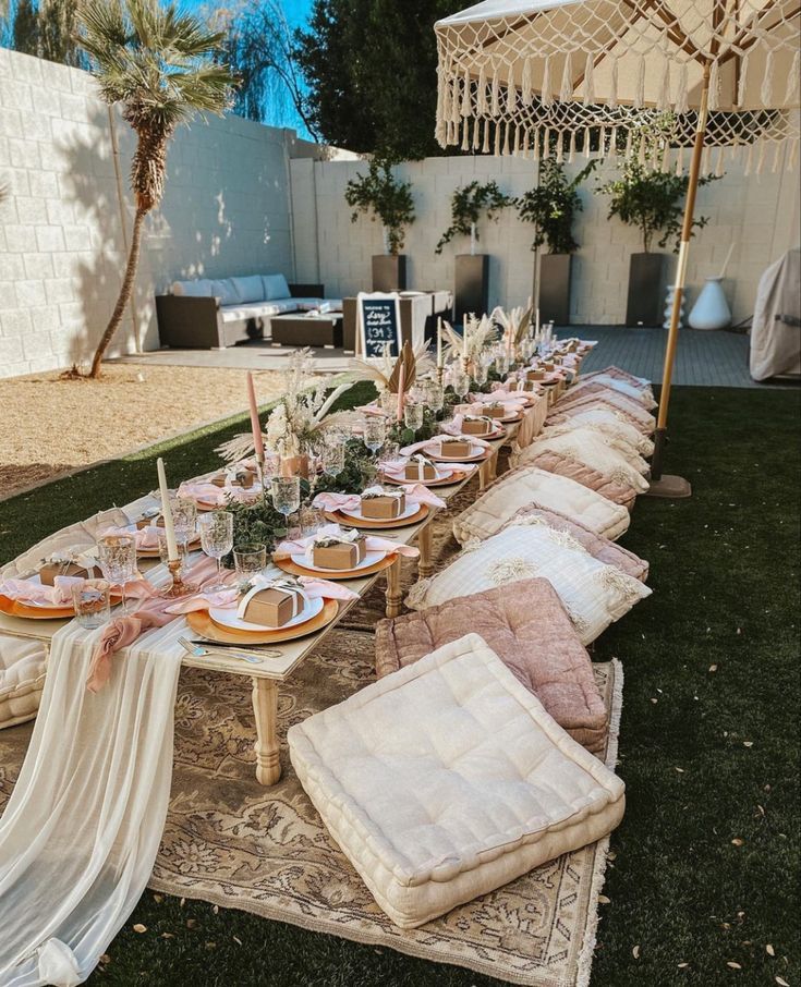 a long table set up with plates and place settings for an outdoor dinner in the backyard