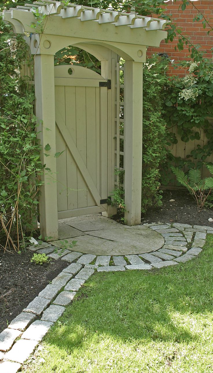 a small garden with a stone path leading to an open wooden door and brick walkway