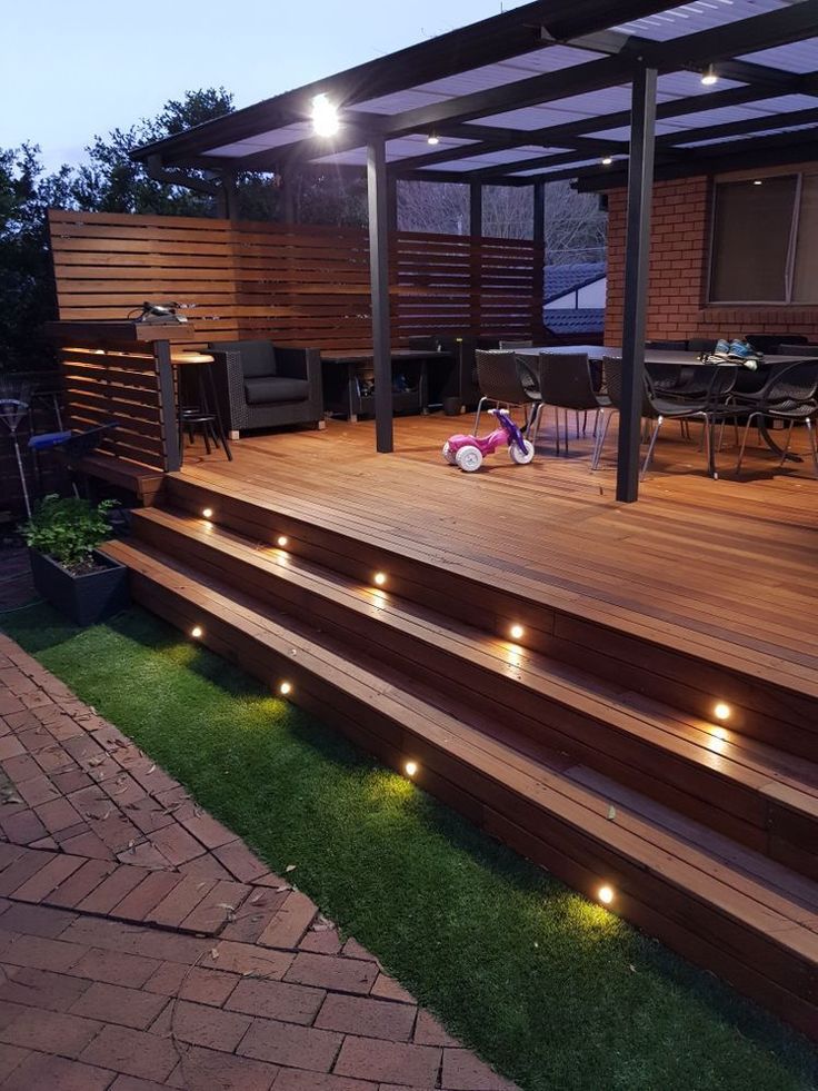 a deck with lights on it next to a table and chairs