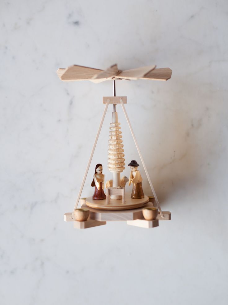 two figurines sitting on top of a wooden balance scale with one man and the other woman