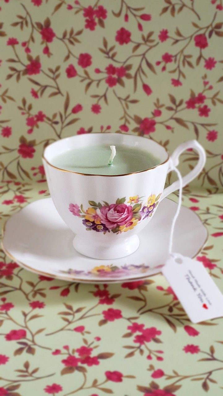 a tea cup and saucer on a floral tablecloth with a price tag attached