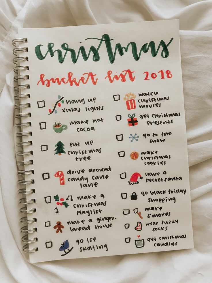 a spiral notebook with christmas stickers on the cover, sitting on top of a bed