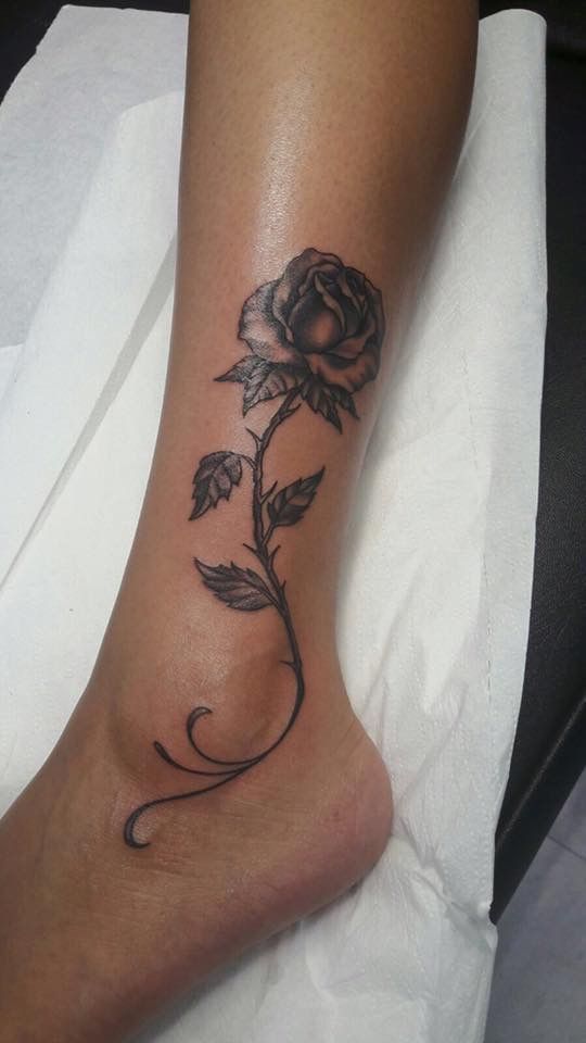 a rose tattoo on the foot of a woman