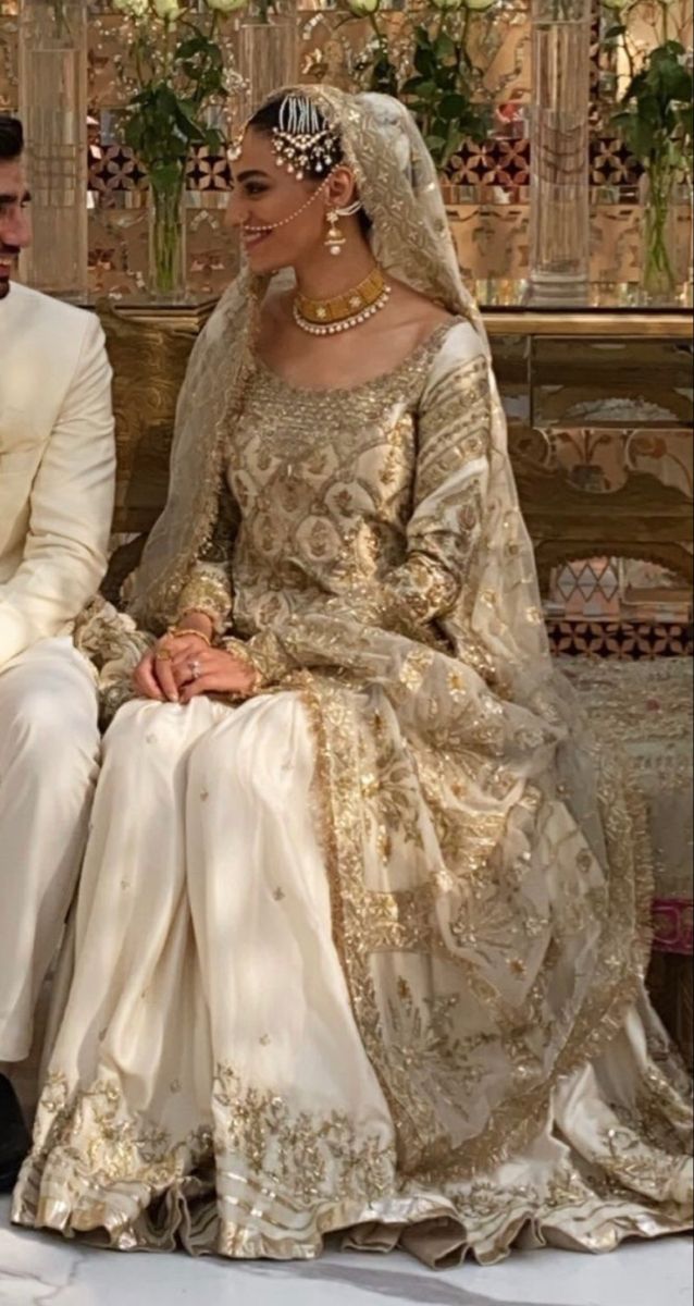 a man and woman dressed in wedding attire sitting on a bench next to each other