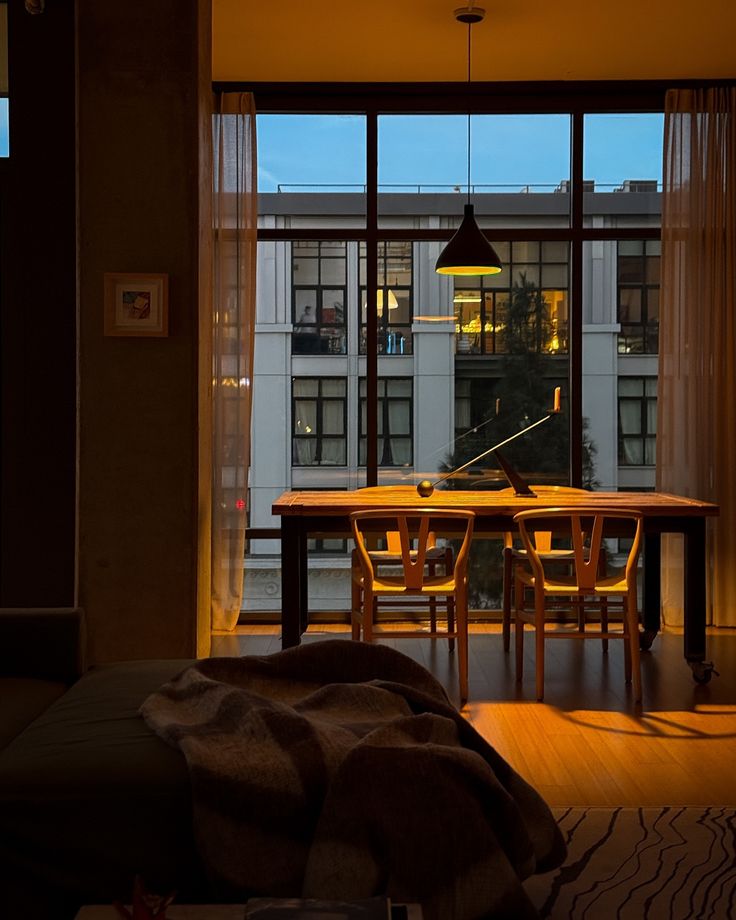 a dining room table and chairs in front of a large window with city lights on it